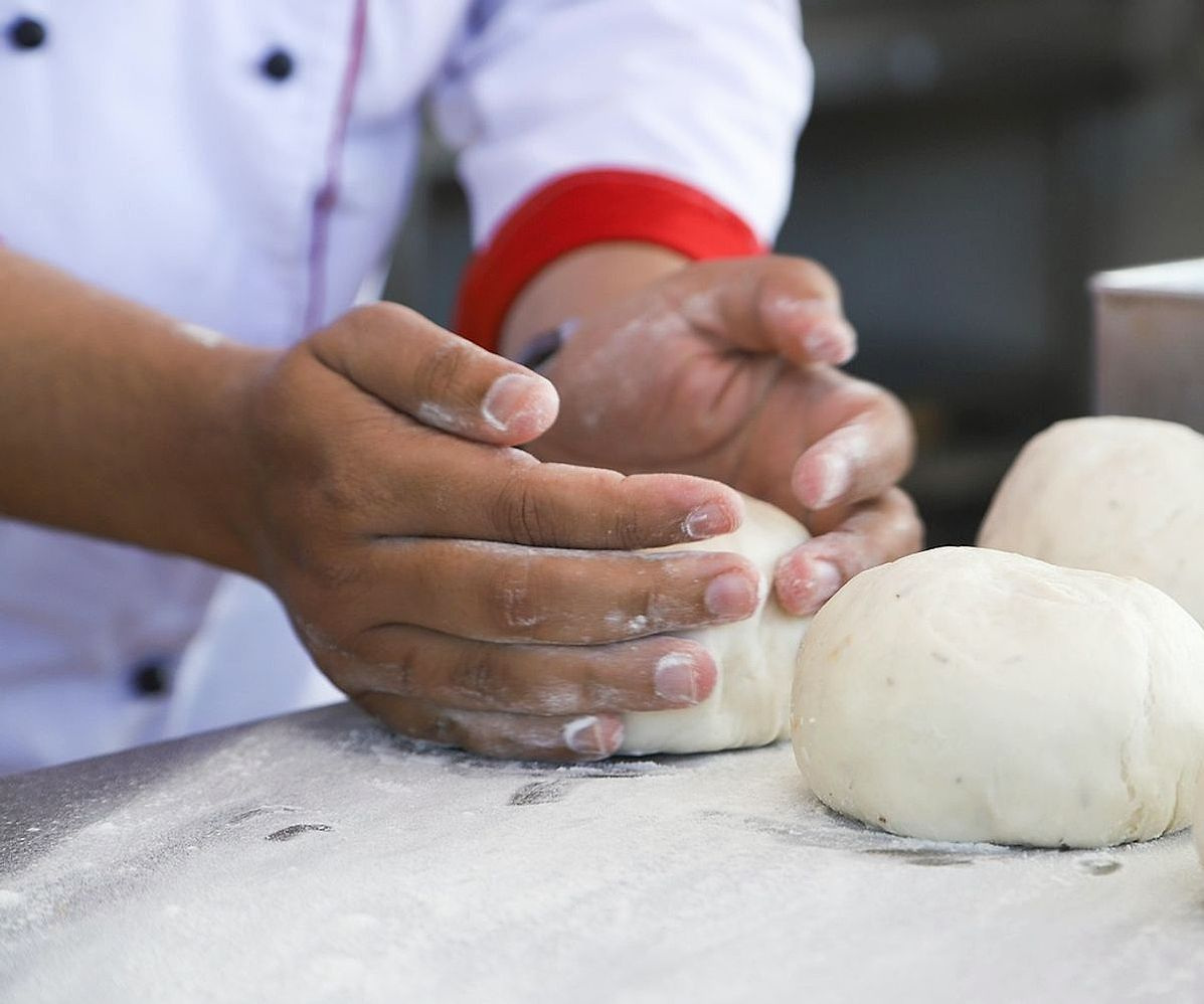 Baker's hands folding chocolate into cake batter